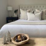 Beige buttoned bed frame, styled with festive potpourri and Christmas trees