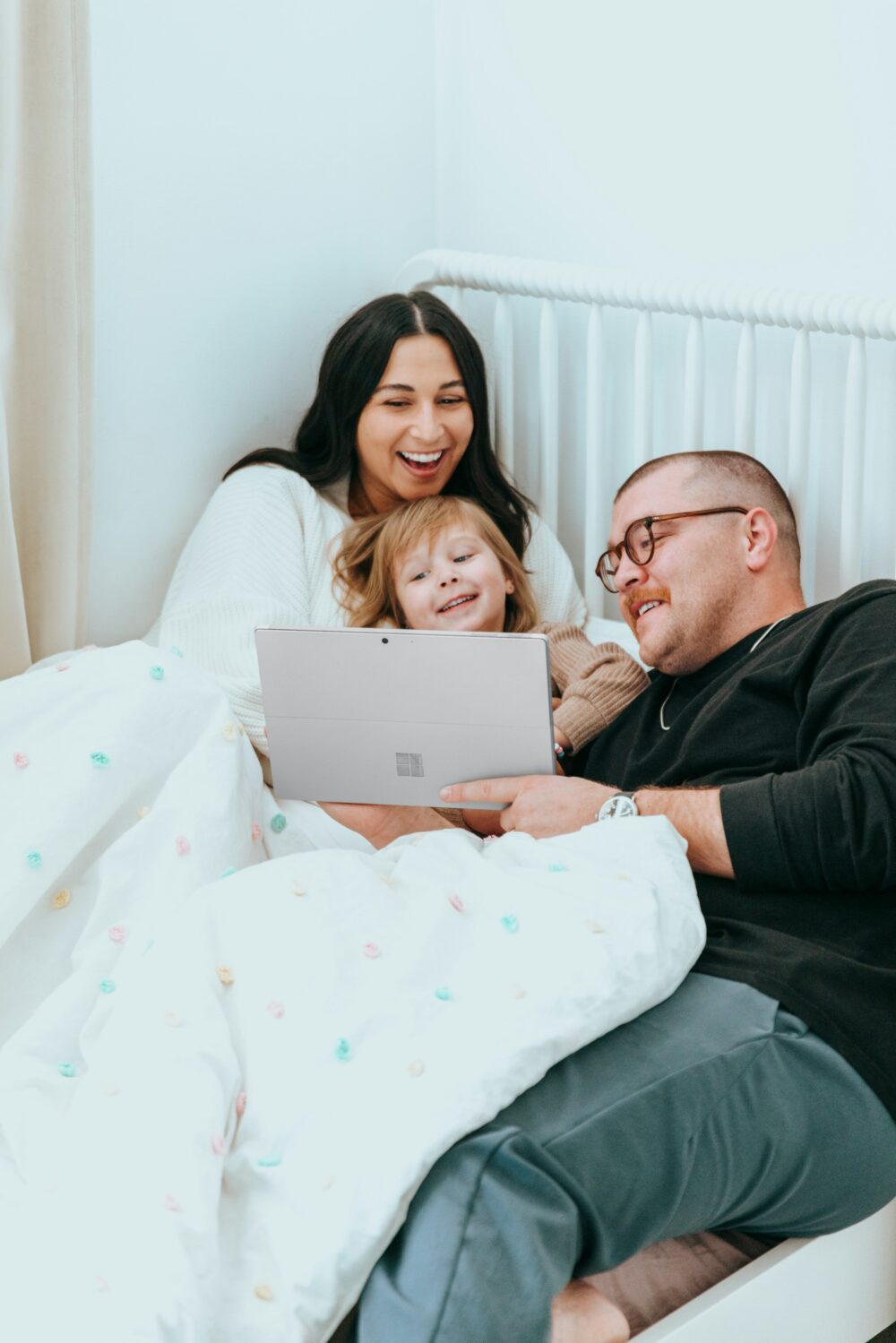 Family of three in bed looking at a tablet